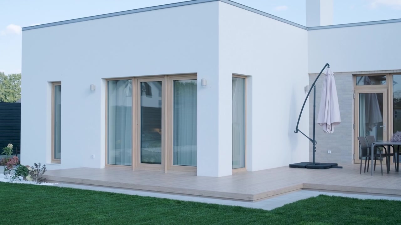Esterno di una moderna casa bianca con terrazza in legno e mobili da giardino