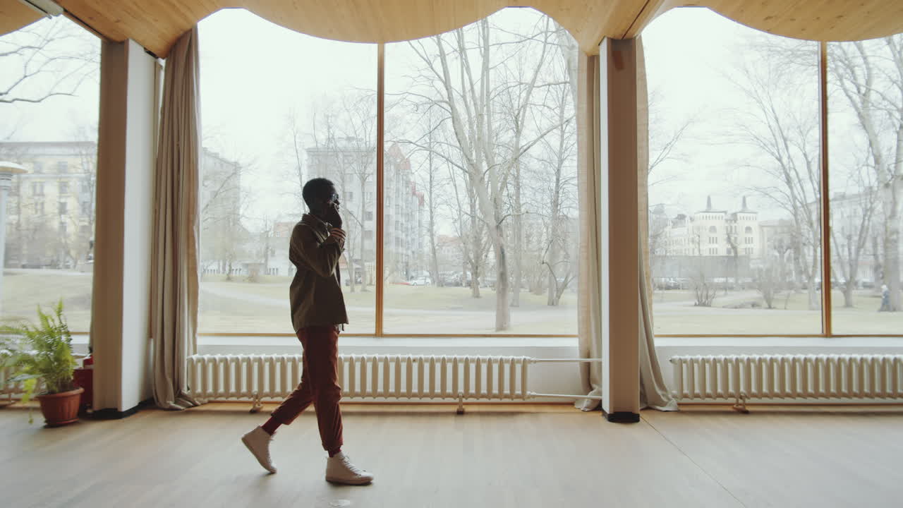 Man Walking in Library Auditorium and Speaking on Phone
