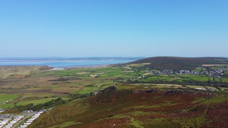 aerial view over caravan camping holiday park with llangenith village with loughor estuary with pembrey in distance background with natural moorland with paths in foreground in wales uk 4k