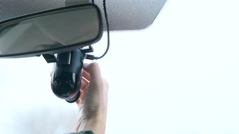 close-up of hands inserting a sd card into dashboard camera mounted under a rear-view mirror