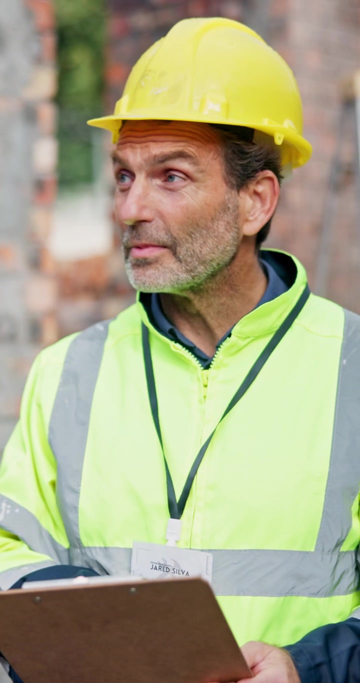Construction Site Manager Reviewing Plans on Clipboard