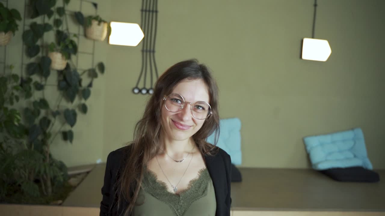 zoom en la cara joven de cabello oscuro estudiante europea mirando a la cámara diciendo sí, de acuerdo, hazlo sonriendo y usando anteojos