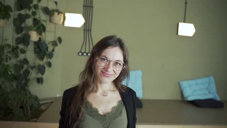 Zoom-on-face-Young-of-dark-hair-female-European-student-looking-at-camera-saying-yes-agree-do-it-smiling-and-wearing-eyeglasses