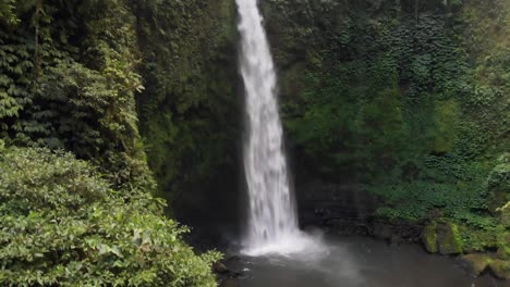 nungnung falls, a spectacular cascading waterfall deep in the jungles of bali, indonesia, is captured in a descending drone shot