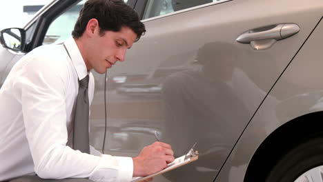 un hombre de negocios comprobando la pintura de los coches.