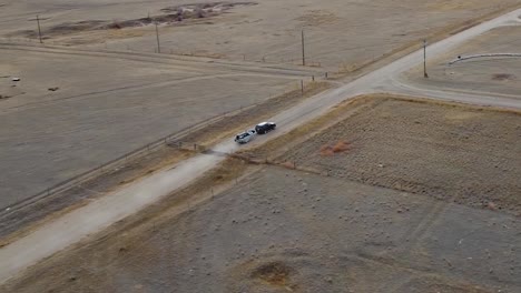 un pequeño bote conectado a la parte trasera de una camioneta que conduce por un camino de tierra en el campo cerca de alberta, canadá, filmado en el aire desde un dron