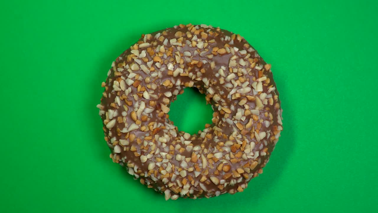 donut salpicado sabroso y fresco macro disparo de primer plano girando sobre un fondo verde. donut muy dulce girando.