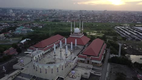aerial view of the great mosque of central java (majt) in suset time. th sun is orange and the weather is cloudy. the mosque have some umbrella that is closed