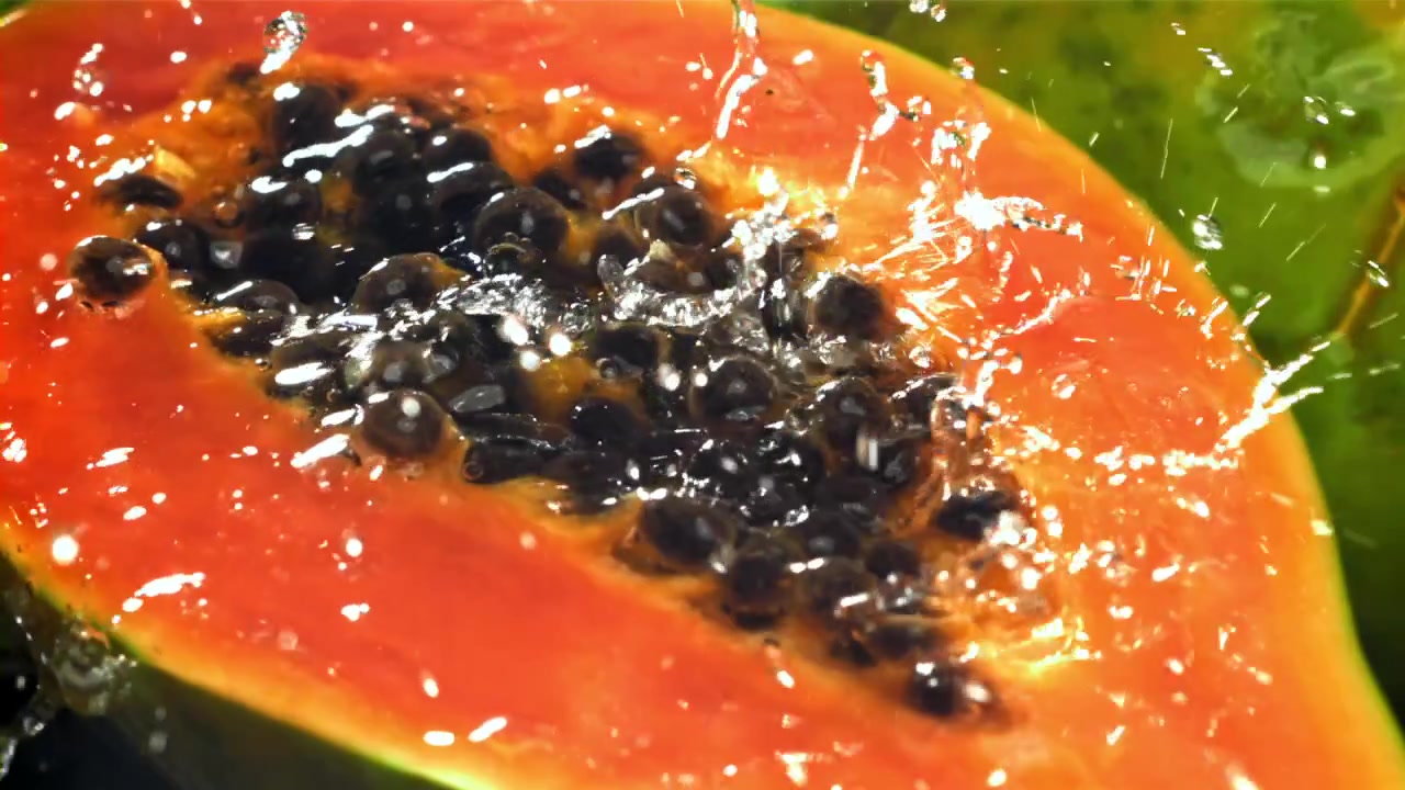 Acqua che schizza su metà di papaya fresca al rallentatore