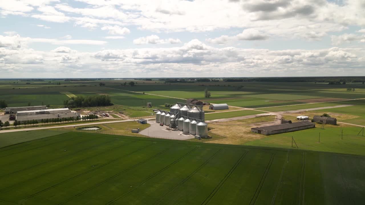 vista de aviones no tripulados de silos agrícolas, graneros, plantas de fabricación, almacenamiento de productos agrícolas y elevadores de granos en el medio de un campo cultivado verde, zoom en