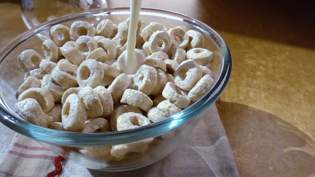 copos de avena crujientes en un tazón para un delicioso desayuno matutino con leche. cámara lenta con toma de seguimiento de rotación.