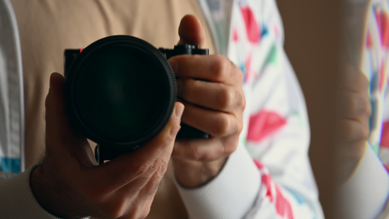 Close up of a man's hands holding a camera with a large lens, preparing to shoot