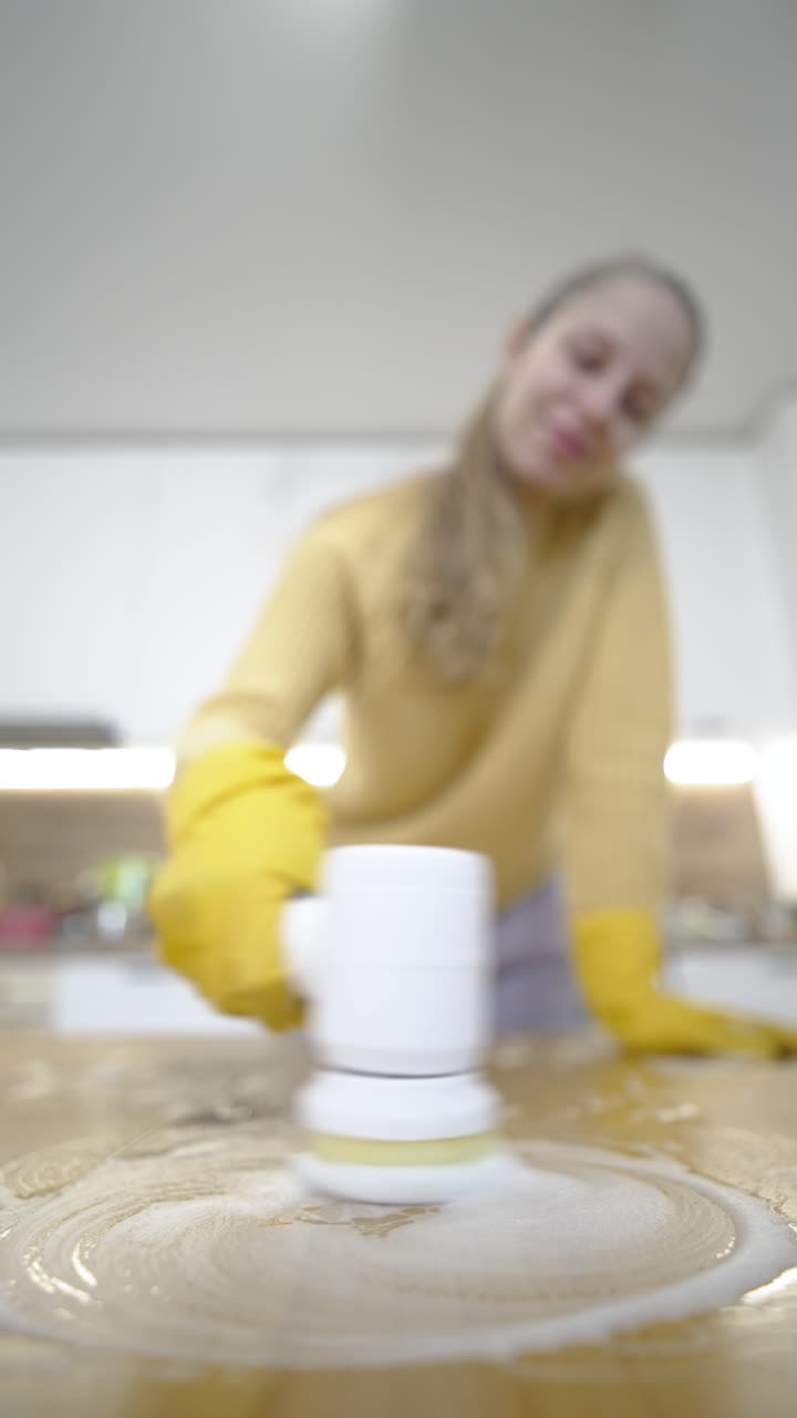 Vídeo vertical mostra uma mulher usando uma ferramenta de limpeza elétrica em uma mesa, destacando a limpeza doméstica moderna, a eficiência e a rotina de faxina de primavera em ambientes internos