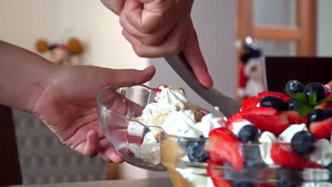 stable shot of a hand scooping a serving of fruity dessert into a bowl at a buffet