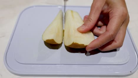 hands slicing a pear on a cutting board