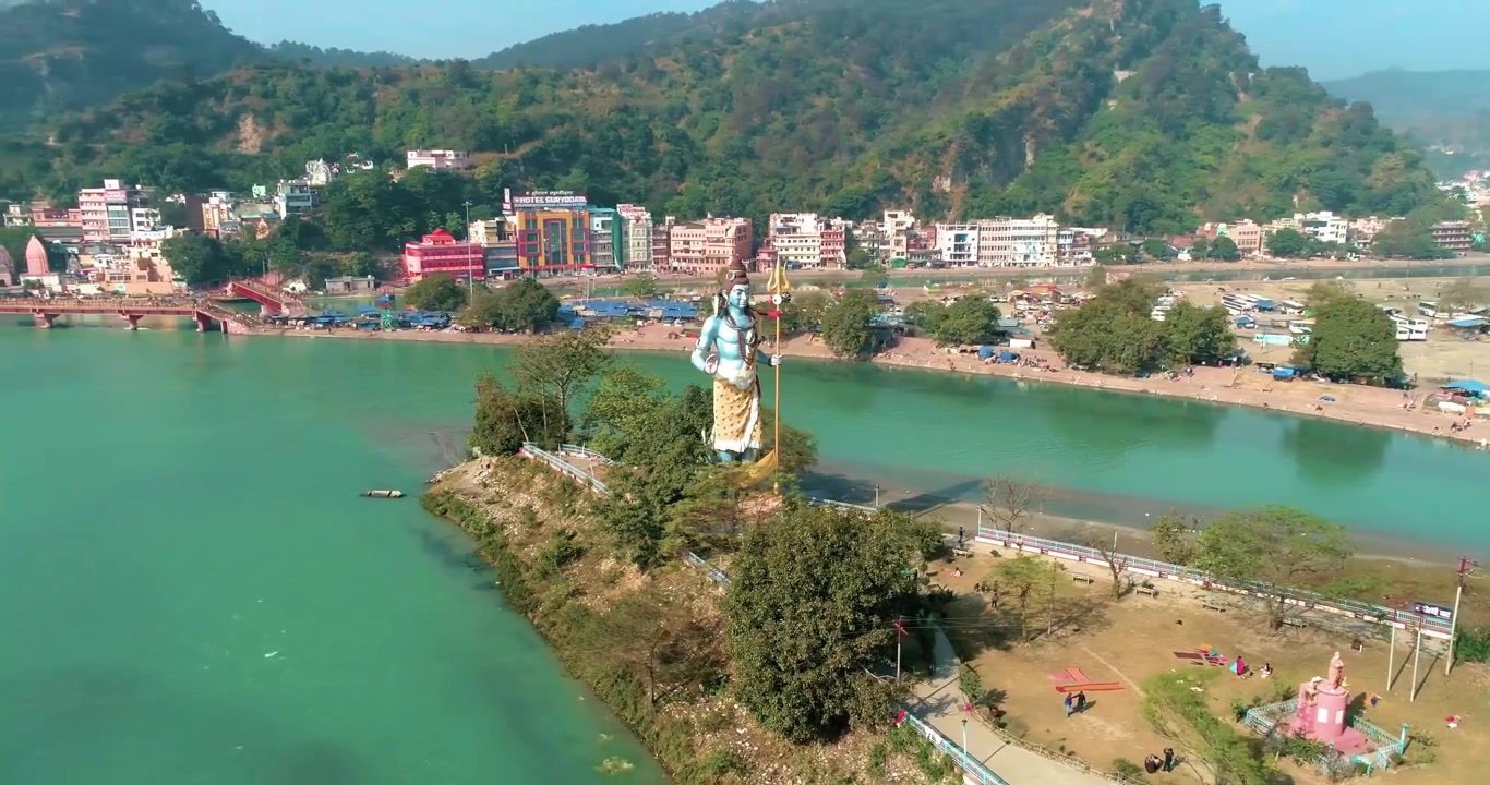 Una toma lateral frontal de una gran estatua del dios hindú Shiva observando los sagrados Ghats del Ganges en el lugar sagrado Haridwar, Uttarakhand, India.