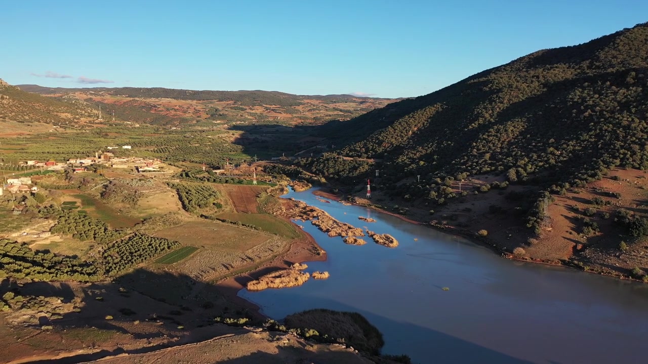 Vista aerea cinematografica con drone di un lago di montagna e di una valle rurale durante l'ora d'oro nel Medio Atlante, Marocco, ideale per progetti di viaggio, natura e campagna