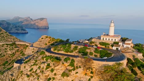 Golden-hour-glow-illuminates-Formentor-lighthouse,-Serra-de-Tramuntana-Mallorca-Spain-and-winding-road