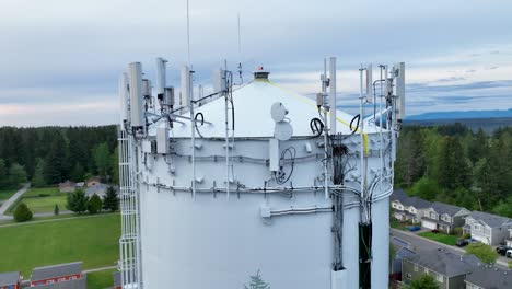 primer plano aéreo de las muchas piezas de equipos de telecomunicaciones en la parte superior de una torre de agua