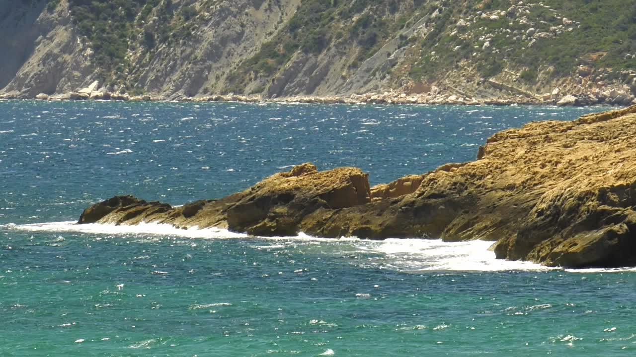 paisaje marino de la costa rocosa con mar azul y olas rompiendo en las rocas, cámara lenta