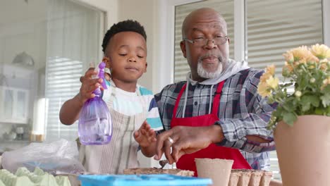 African-american-grandfather-and-grandson-embracing,-planting-flowers-on-balcony,-slow-motion