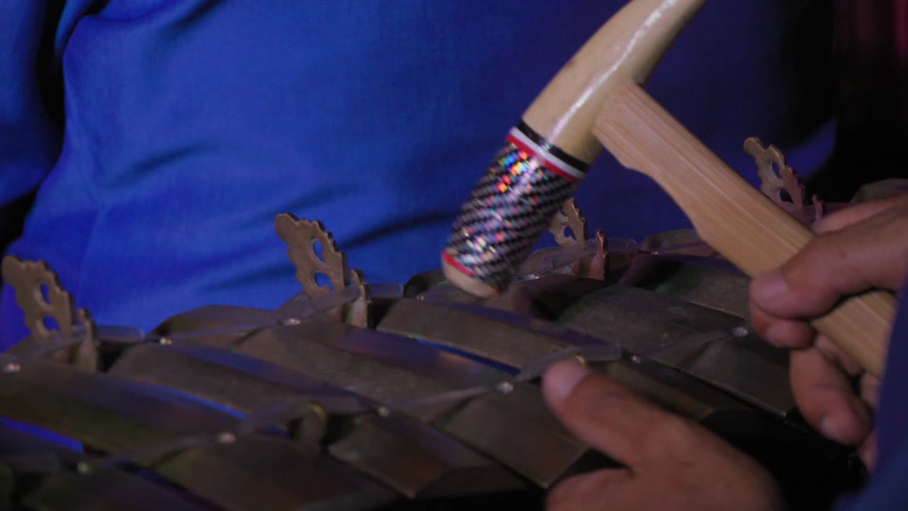 vista detallada de un jugador de gamelan en bali, indonesia, golpeando hábilmente el instrumento con un martillo vibrante