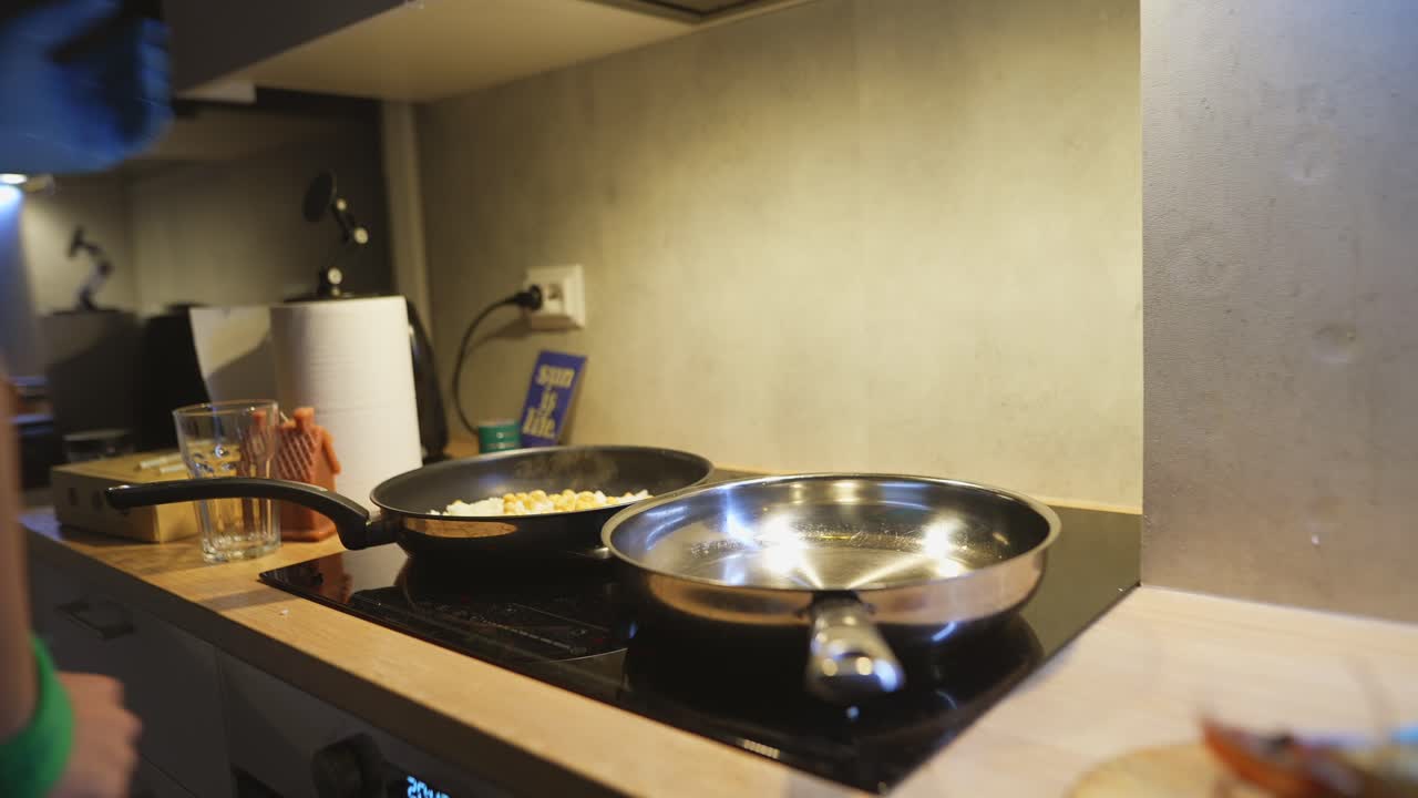 Persona con guanti blu che cucina cibo in padella sul piano cottura