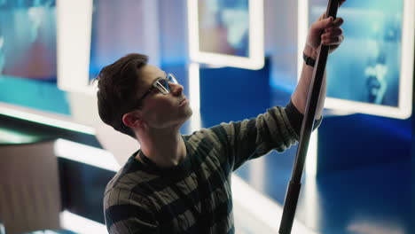 technician adjusting boom pole in broadcast studio, preparing for shot. focused on task in professional media production setup with visible camera equipment and studio lighting