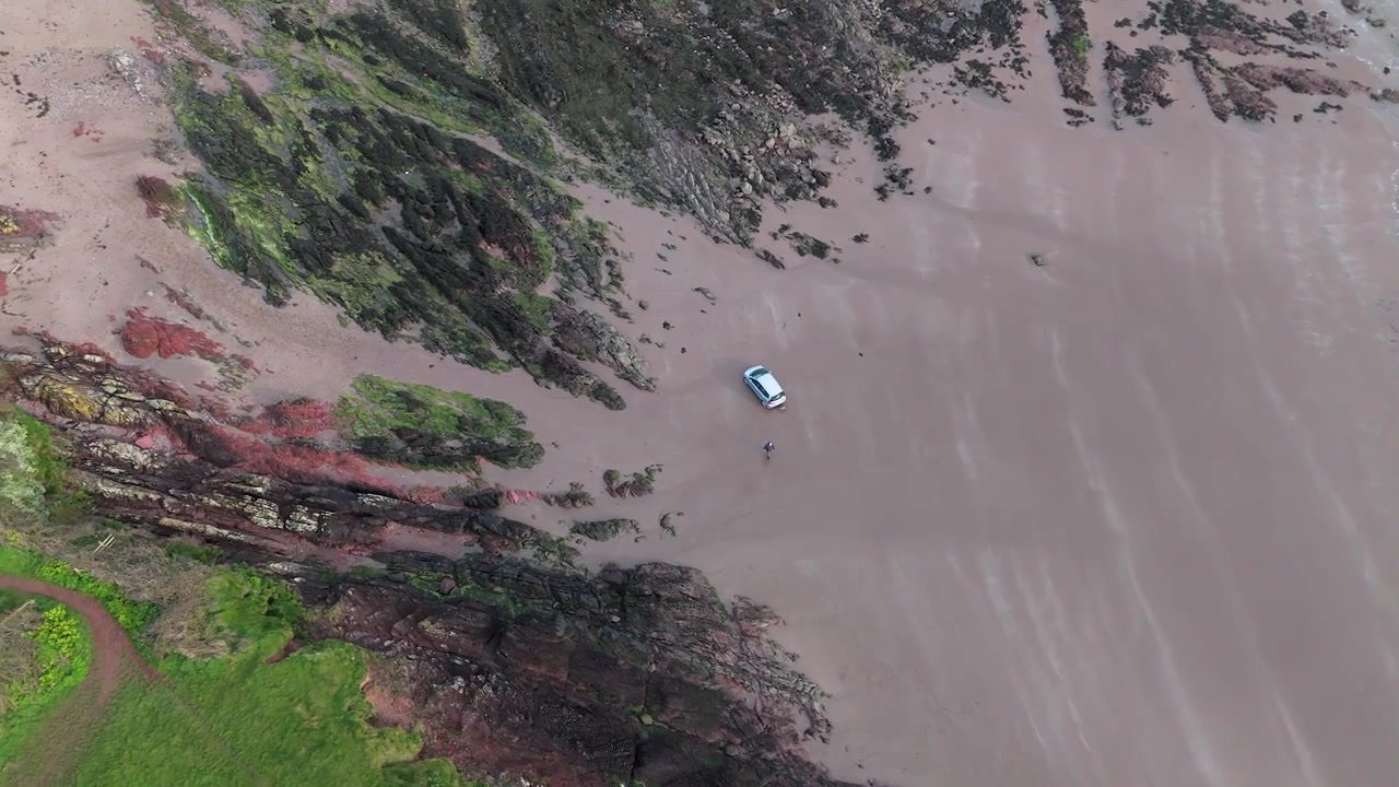 Coche aparcado en la cala de arena de Sleeping Bay en Milford Haven, vista aérea sobrevolando la cima del acantilado