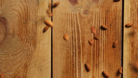 overhead shot of almond nuts dropping onto wooden surface shot in slow motion 1