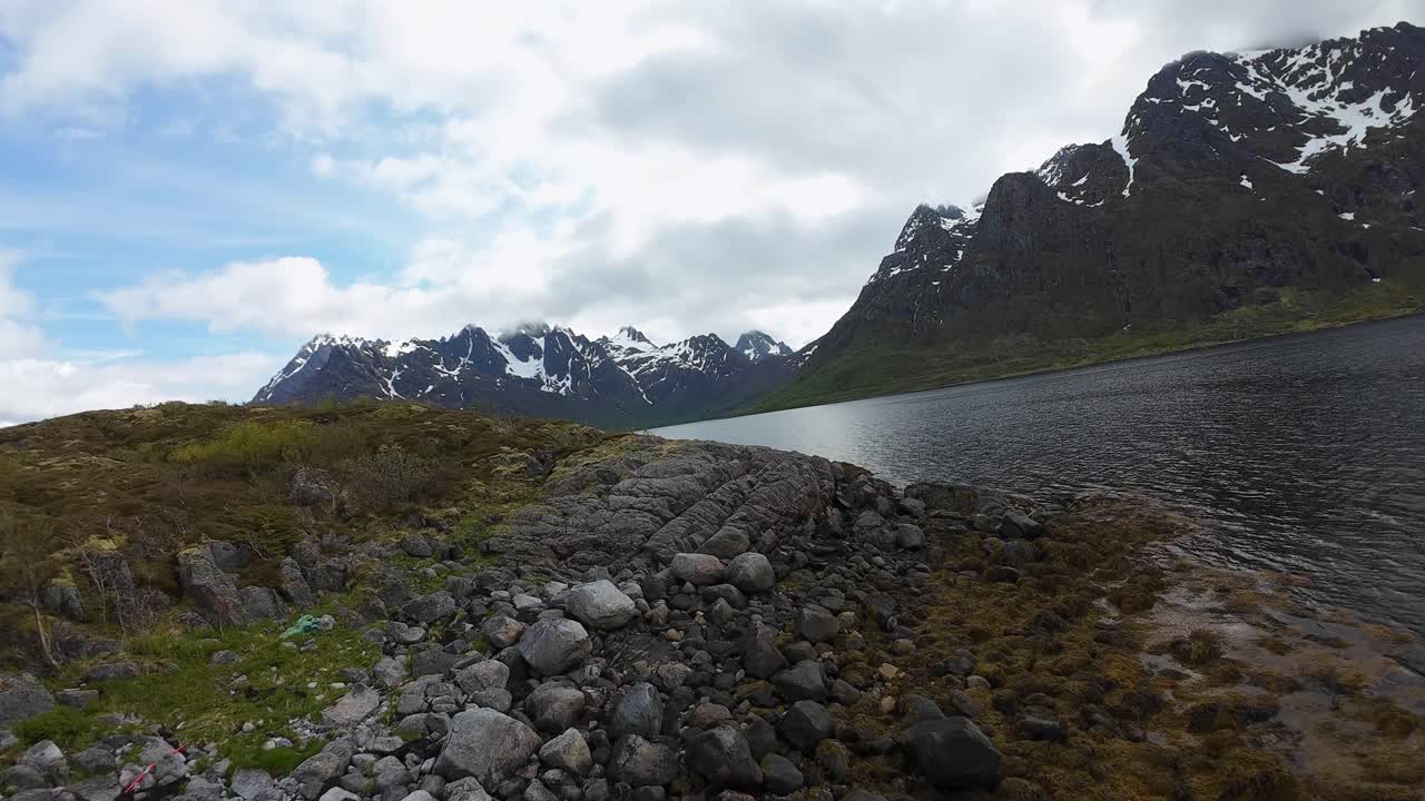 FPV drone glides above rocky shore at Austnesfjorden near E10 before turning toward Lofoten peaks