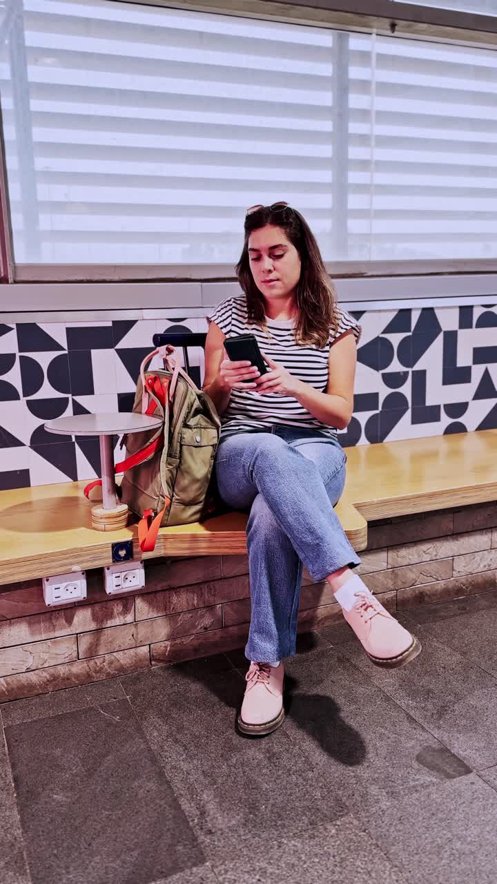 Young Woman Waiting With Backpack And Checking Mobile Phone