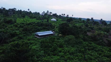 aerial of a large warehouse in the green hills of the nigerian countryside. standalone poultry in the middle of thick nature forest, jungle in africa