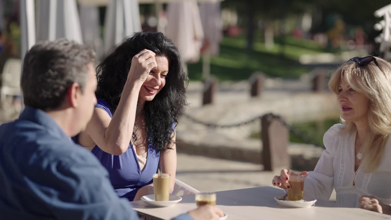 Tre amici che bevono caffè e conversano in un caffè all'aperto