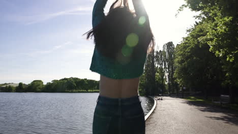 portrait of a fashionable and beautiful italian model walking in a tranquil park wearing a shimmery sweater in london, united kingdom