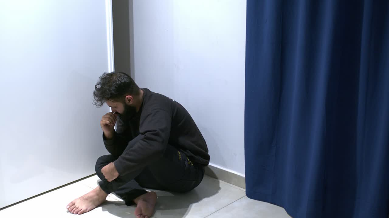 Man suffering psychotic episode looking at the mirror with hallucinations, left alone