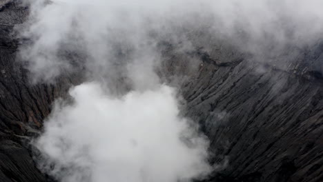 man running on peak of volcano, aerial push revealing active mt bromo