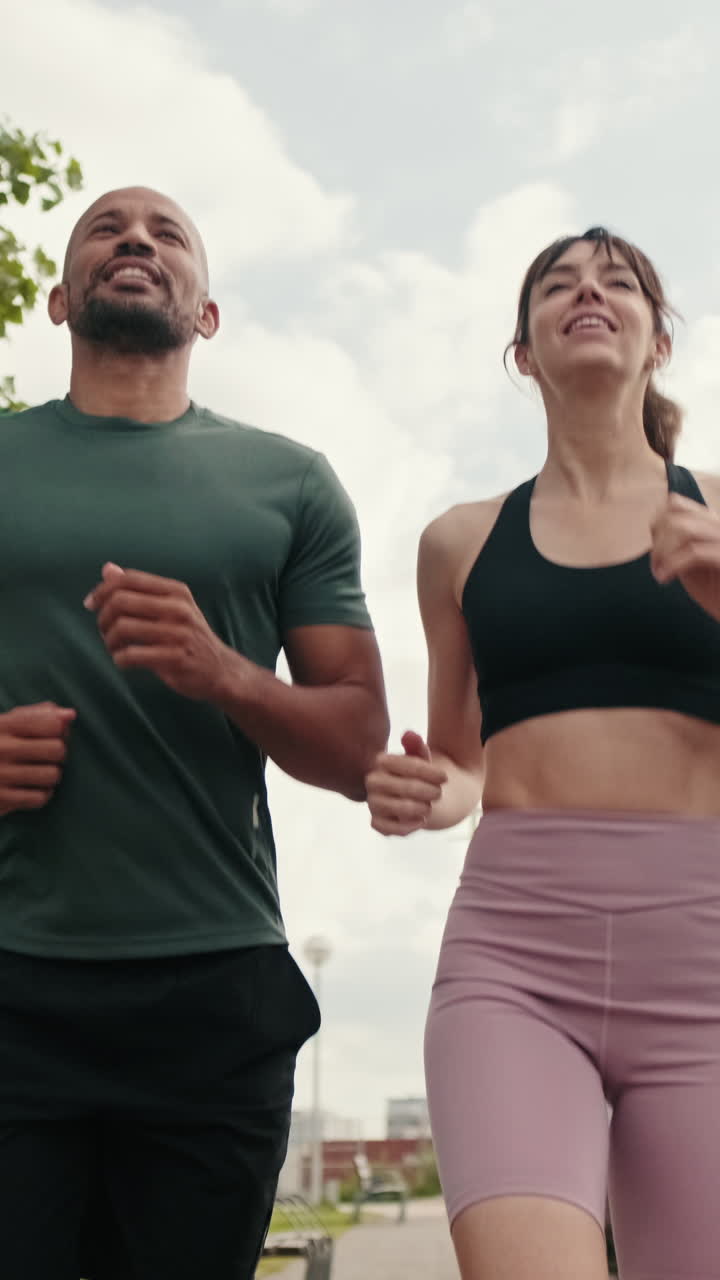 Uomo e donna che corrono insieme all'aperto in un parco urbano