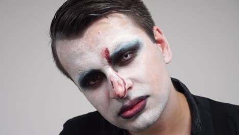 face painted man showing tongue and devil horns fingers, closeup portrait