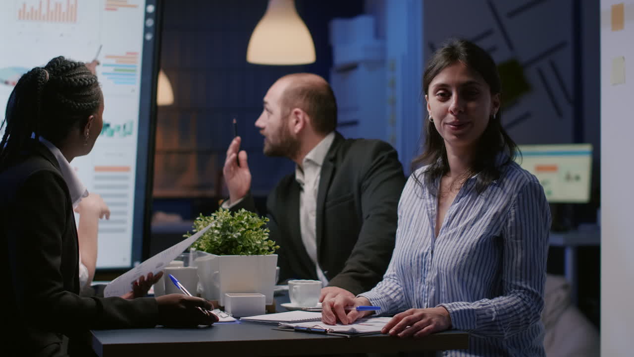Portrait of businesswoman sitting at conference table in office meeting room working overtime