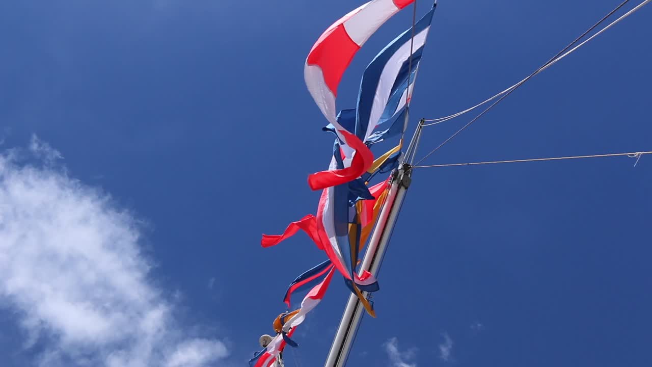 구름과 하늘을 배경으로 보트 돛대에서 강한 바람에 날리는 다양한 다채로운 깃발까지 이동