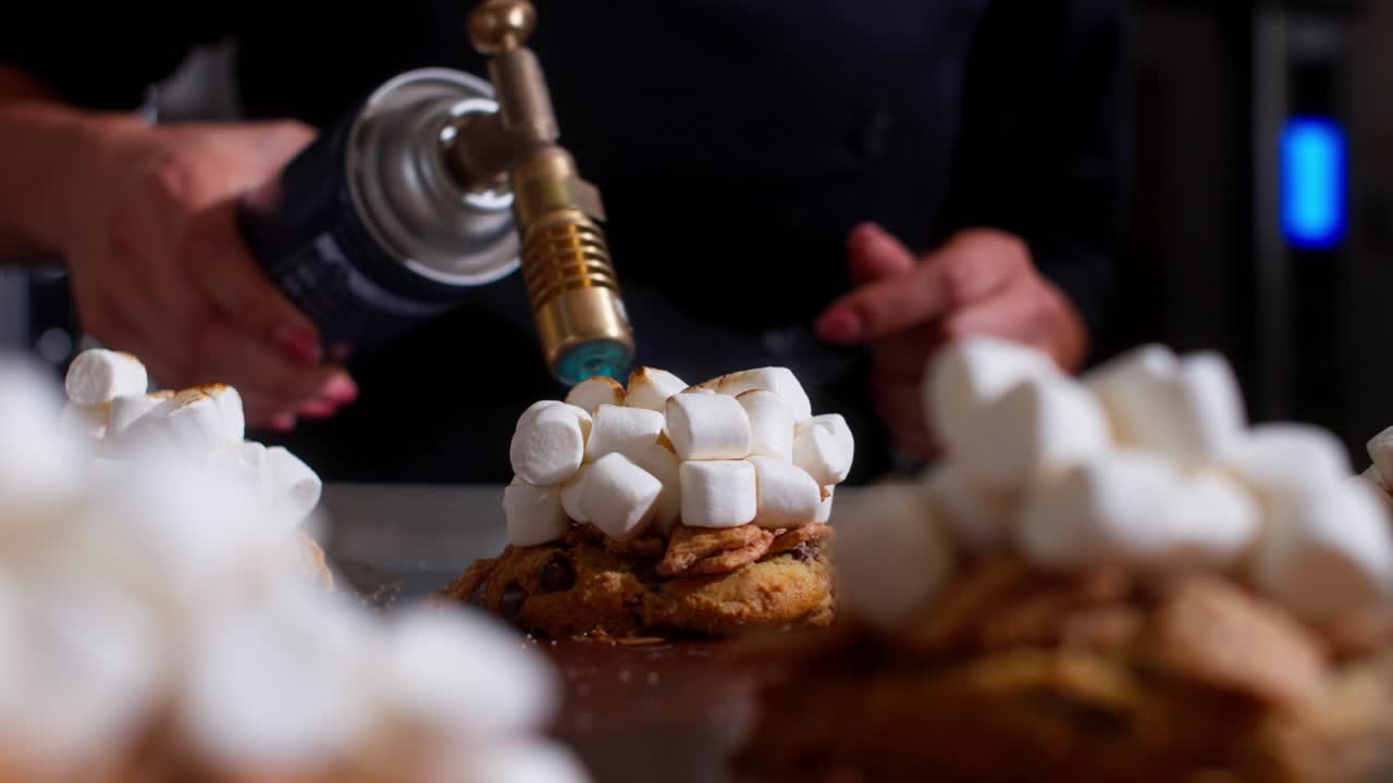 Marshmallow tostati con un cannello da cucina su biscotti a una postazione dolci