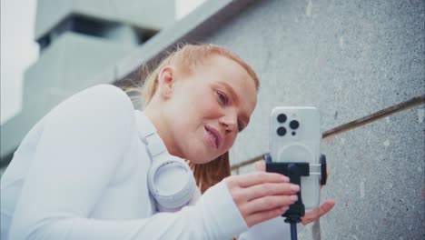 woman filming with smartphone and headphones outdoors