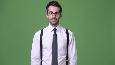 joven empresario persa barbudo y guapo contra un fondo verde