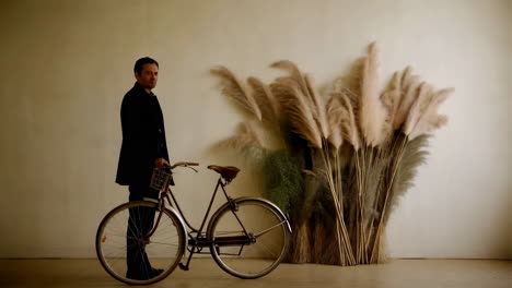 man posing with bicycle and pampas grass