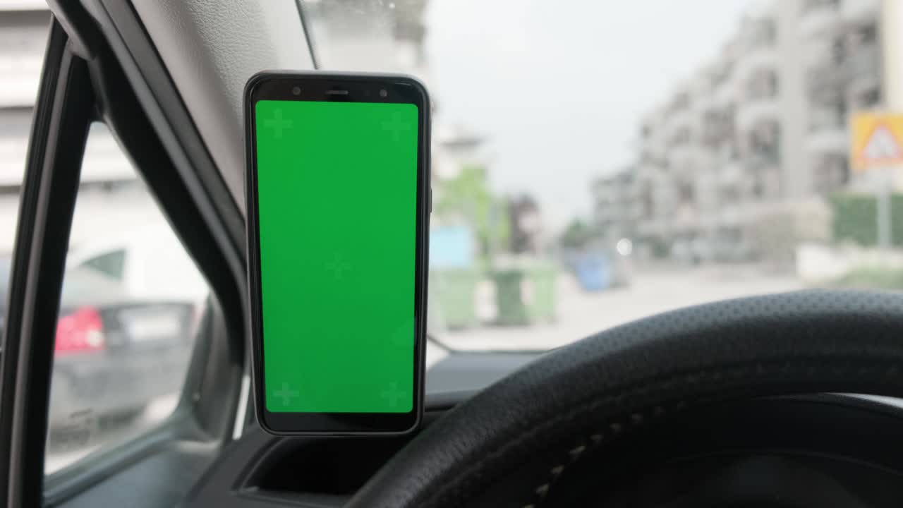 una maqueta de teléfono inteligente de pantalla verde dentro del coche durante la conducción.
