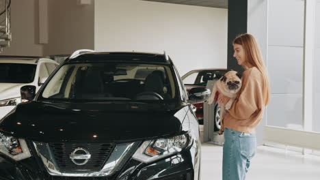 mujer con perro pug en el concesionario de coches