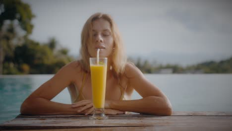 woman enjoying a smoothie by the pool