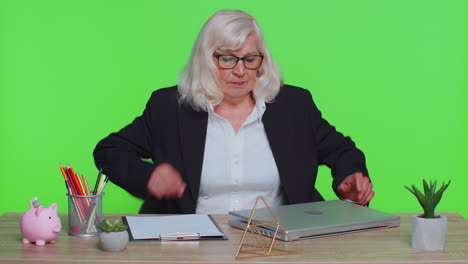 smiling mature business woman sits at workplace office desk, opening laptop computer, start working