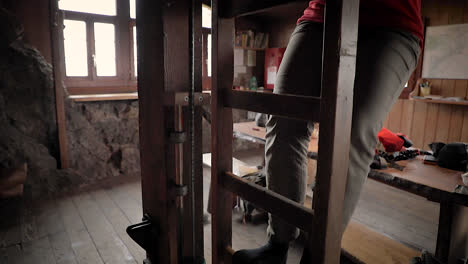 person climbing up ladder in a rustic wooden log cabin